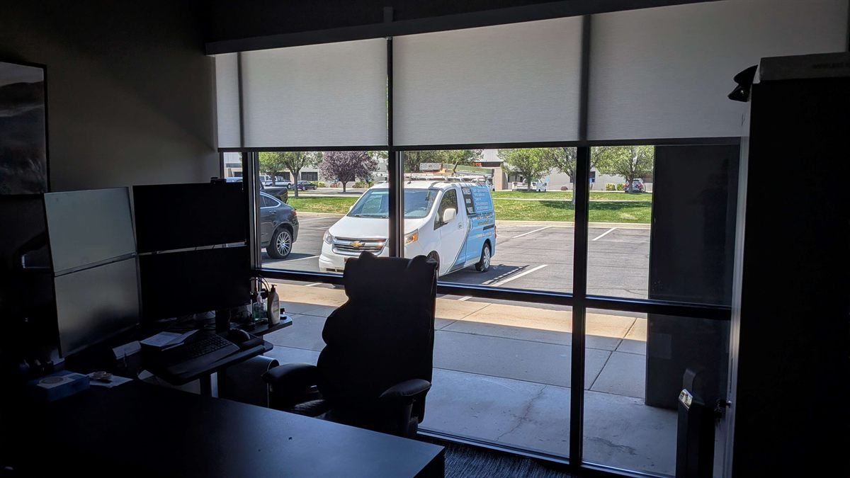 Large motorized roller shades on the glass storefront of a Salt Lake City office